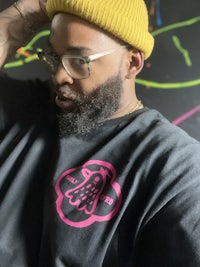 a man wearing a yellow beanie and a black t - shirt