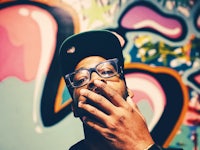 a man wearing glasses and a hat is smoking a cigarette